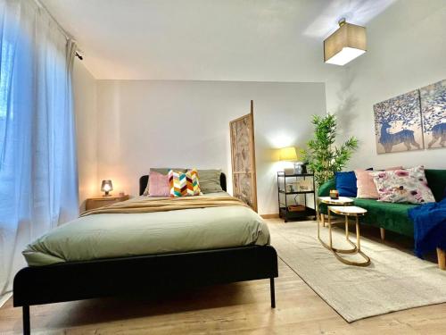 ein Schlafzimmer mit einem Bett und einem Sofa in der Unterkunft Studio avec parking privé et lave-linge, coeur de Fronton in Fronton