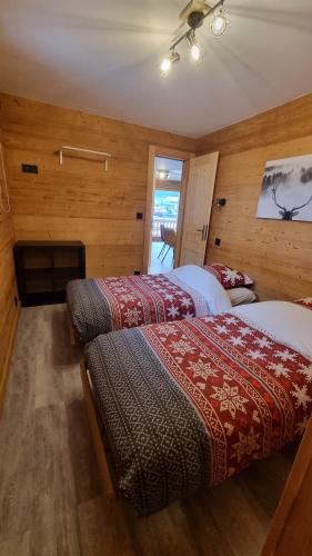 Duas camas num quarto com paredes de madeira em L'Étoile du Linga em Châtel