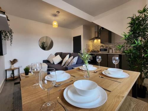 a wooden table with plates and wine glasses on it at SuperValue Suite 3 - Fast WiFi, Hotel Linen, Keyless Entry, City only 10 Mins - BY PROPERTY PROMISE in Cardiff
