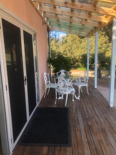 Un patio con una mesa y sillas en una terraza. en Danara Cottage, en Bathurst