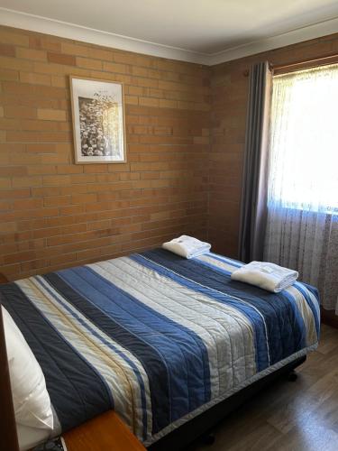 a bedroom with a bed with a brick wall at Emu Beach Chalets in Albany