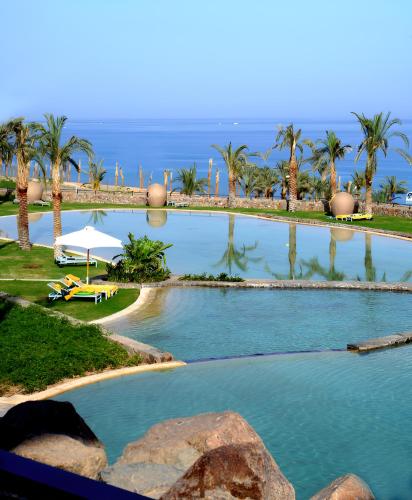 a large swimming pool with palm trees and a beach at Retac Qunay Dahab Resort & SPA in Dahab