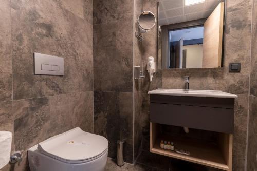a bathroom with a toilet and a sink and a mirror at IRENIC HOTEL in Antalya