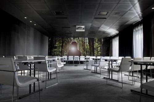 a room with tables and chairs and a person in the background at Carbon Hotel in Genk