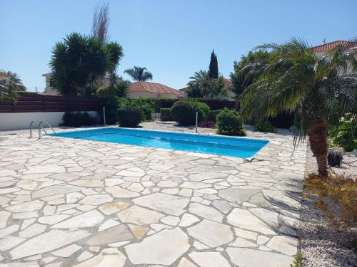 a swimming pool in a yard with a stone patio at Villa Penny in Pissouri