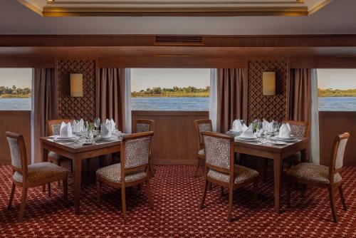 een eetkamer met tafels en stoelen en uitzicht op het water bij JAZ Elite Senator Nile Cruises - Every Thursday from Luxor for 07 Nights & Every Thursday from Luxor for 05 Nights in Luxor