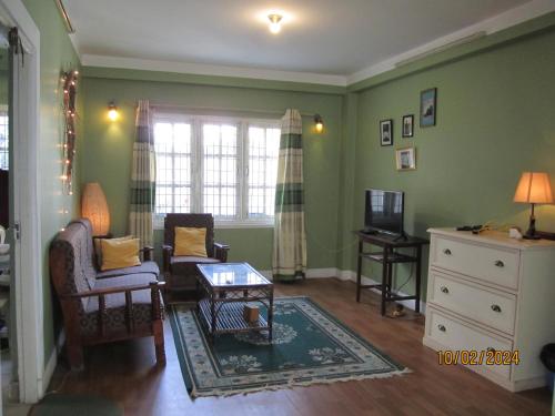 sala de estar con paredes verdes, mesa y sillas en KAJI HOME, en Pātan