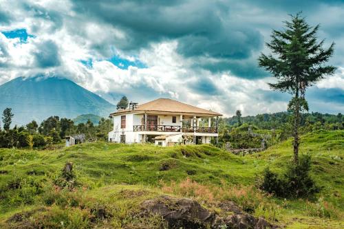 a house on a hill with a mountain in the background at Kinigi Cottage in Kinigi