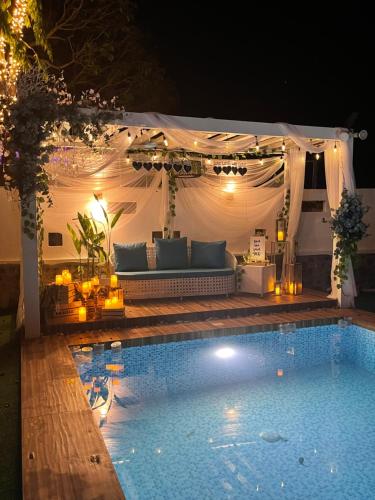 a swimming pool in front of a tent with a couch at CasaDel Beach House in Mabini