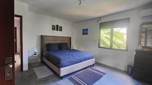 a bedroom with a bed with a blue comforter and a window at Villa North Coast in Trou aux Biches