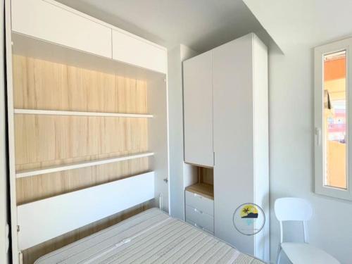 Schlafzimmer mit weißen Schränken, einem Bett und einem Fenster in der Unterkunft Modern studio apartment at Monaco,La Manga in La Manga del Mar Menor