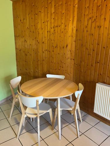 a wooden table with two chairs and a wooden wall at Logis Le Chalet in Saint-Maurice-en-Trièves