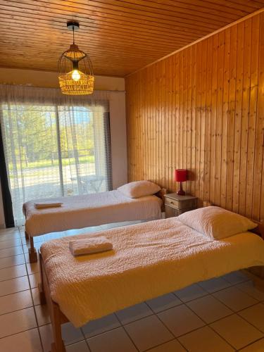 a bedroom with three beds and a chandelier at Logis Le Chalet in Saint-Maurice-en-Trièves