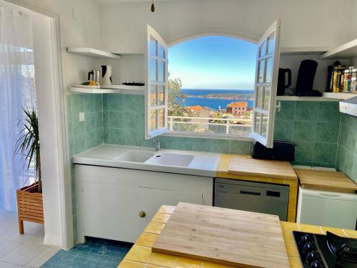 eine Küche mit einem Waschbecken und einem Fenster in der Unterkunft Villa Montalbo vue mer de 2 à 10 personnes in Cargèse
