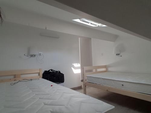 Cette chambre blanche comprend 2 lits et un sac à dos. dans l'établissement APPARTEMENT T3 - au calme - climatisé - plages à pied, à Sanary-sur-Mer