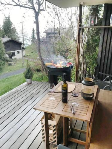 a table with wine glasses and a grill on a deck at Cosy studio on the ski slopes in Gryon