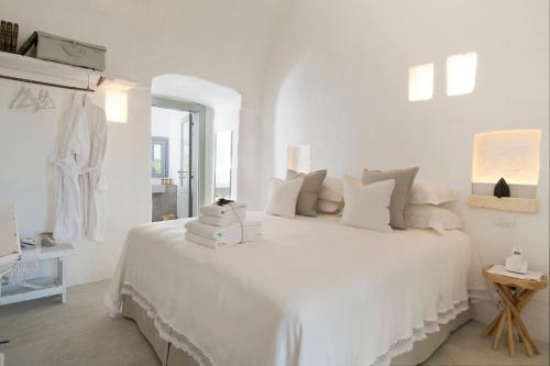 a white bedroom with a large white bed with pillows at Masseria Le Torri in Polignano a Mare