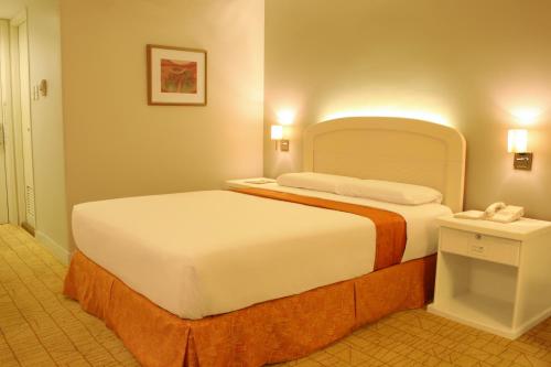 a hotel room with a large bed and a telephone at Riviera Mansion Hotel in Manila