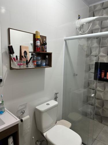 a white bathroom with a toilet and a shower at Sítio Recanto da Mata 1 suíte, 2 quartos, área de piscina, churrasco, área de jogos, campo de vôlei, lago para pesca, moenda de cana e rede para descanso in Marataizes