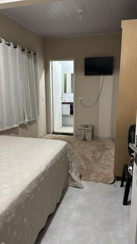 a bedroom with a bed and a flat screen tv at Sítio Recanto da Mata in Marataizes