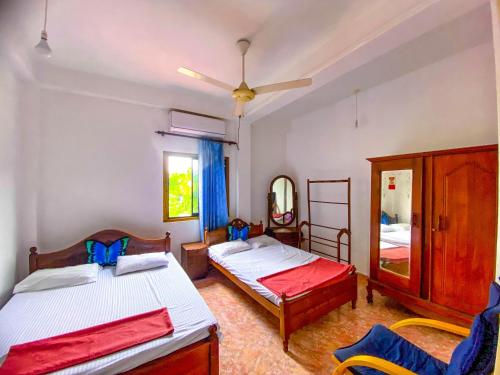 a bedroom with two beds and a mirror at Geesh Residence : Rooms in Jaffna in Jaffna