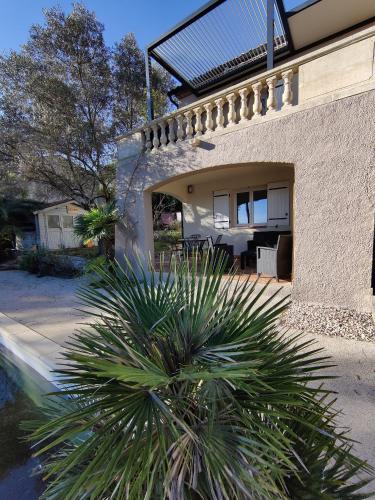 a house with a palm tree in front of a house at appartement indépendant avec vue panoramique in Combaillaux