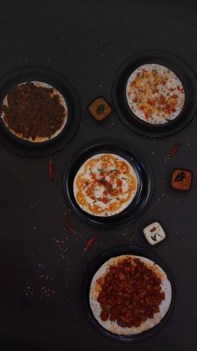 a group of four pizzas sitting on a table at Marari Bobans villa in Mararikulam