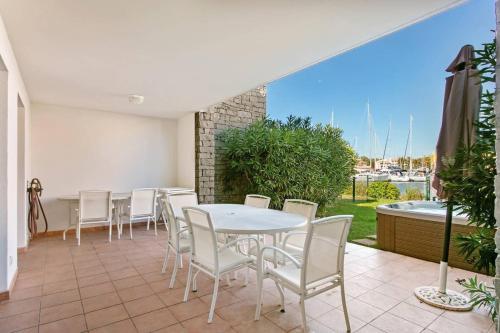 d'une terrasse avec une table et des chaises blanches. dans l'établissement MARINA ILE ST MARTIN Joli 4 pièces avec jacuzzi Cap d'Agde, au Cap d'Agde