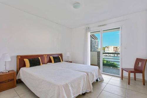 une chambre blanche avec un lit et un balcon dans l'établissement MARINA ILE ST MARTIN Joli 4 pièces avec jacuzzi Cap d'Agde, au Cap d'Agde