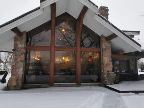 a building with large windows with snow on the ground at Ąžuolas in Kaspariškė