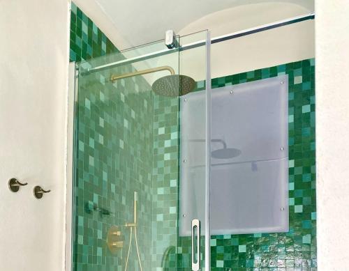 ducha con puerta de cristal y azulejos verdes en Casa 900 en Castellammare del Golfo