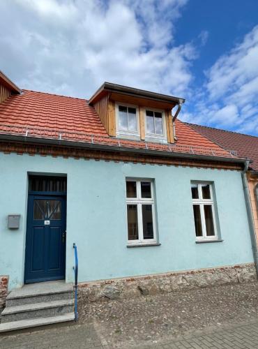 una casa azul con techo rojo y puerta azul en FeWo-Schloßstraße - Zum blauen Haus, en Penkun