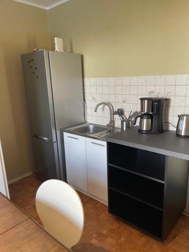 a kitchen with a stainless steel refrigerator and a sink at FeWo-Schloßstraße - Zum blauen Haus in Penkun