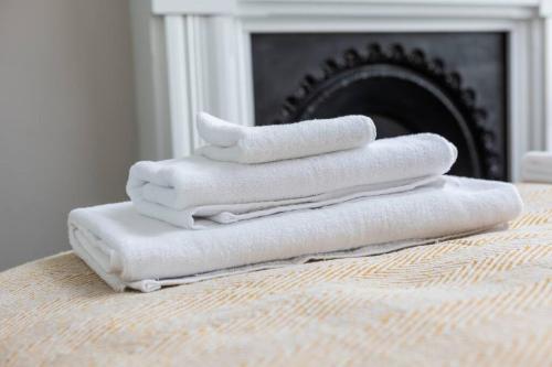einen Stapel Handtücher auf einem Bett mit Kamin in der Unterkunft Stunning 2 Bed in the Centre of Cheltenham! in Cheltenham