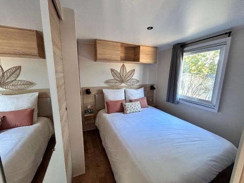 Dos camas en una habitación pequeña con ventana. en Notre bulle du ferret, en Lège-Cap-Ferret