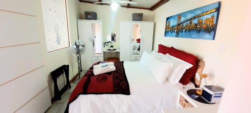 a bedroom with a bed with red and white pillows at Cape Cozy Cottages in Cape Town