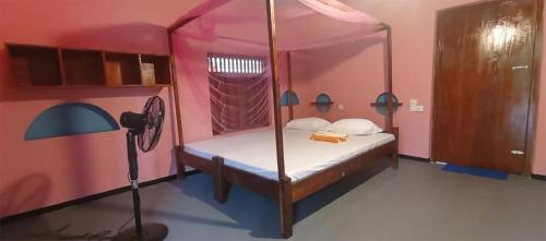a bedroom with a canopy bed in a pink room at Breezy Beach Cabanas in Arugam Bay