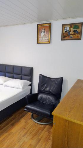 1 dormitorio con 1 cama y 1 silla negra en Room in shared apartment, en Friedrichshafen