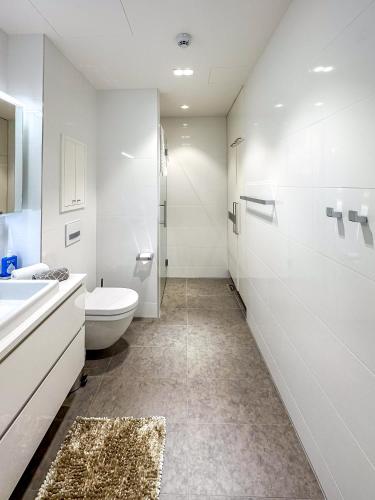 a white bathroom with a toilet and a sink at Regatta Seaside Suite in Hanko in Hanko