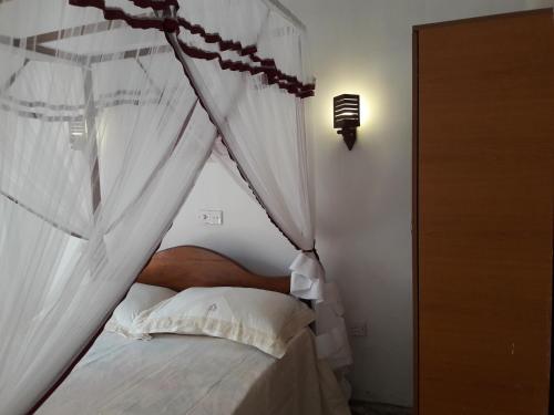 a bedroom with a canopy bed with white curtains at Harmonic villa in Weligama