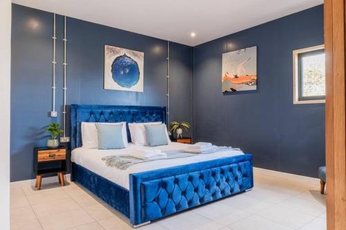 a blue bedroom with a bed with a blue wall at Brick Barn - Luxury Barn Conversion by River Avon! in Cropthorne