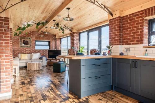 an open kitchen with brick walls and blue cabinets at Brick Barn - Luxury Barn Conversion by River Avon! in Cropthorne