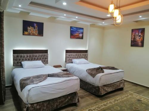 two beds in a room with white walls at شقه فندقيه مواجهه للأهرامات. Hotel Apartment in Cairo