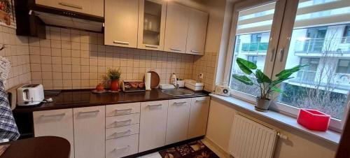 cocina con armarios blancos, fregadero y ventana en Apartament na Bałtyckiej en Kołobrzeg