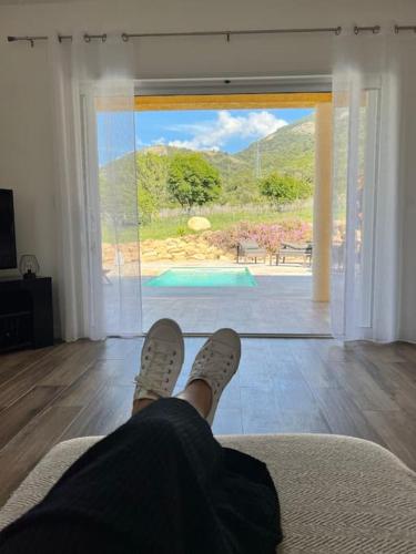 a person sitting on a couch in a living room looking out a door at Très belle villa au calme avec piscine à Sagone in Sagone