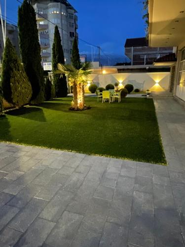 a garden with a palm tree in a building at Rent Rooms Kapri in Pogradec