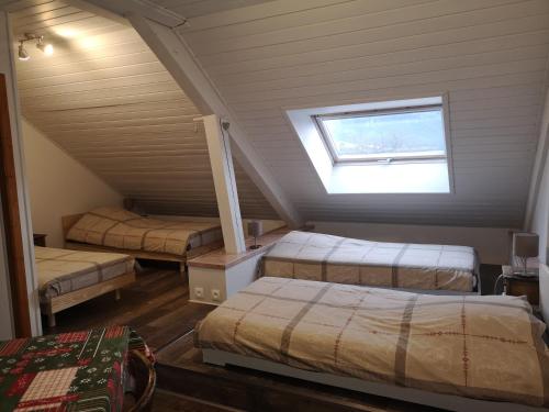 ArithにあるLa Fruitière d'Arithのベッド3台と窓が備わる屋根裏部屋