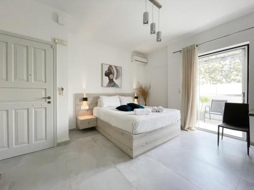 a white bedroom with a bed and a large window at Sunset Seaside Apartments & Studios in Rethymno