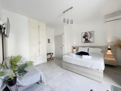 a white bedroom with a bed and a chair at Sunset Seaside Apartments & Studios in Rethymno