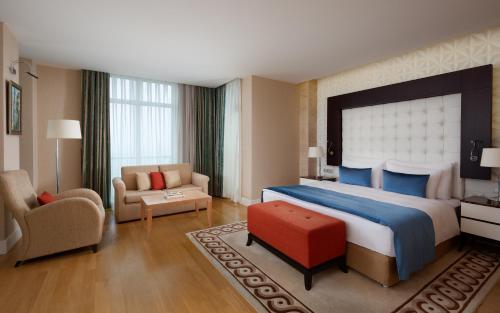 Cette chambre comprend un grand lit et une chaise. dans l'établissement Badamdar Hotel and Residences, à Baku